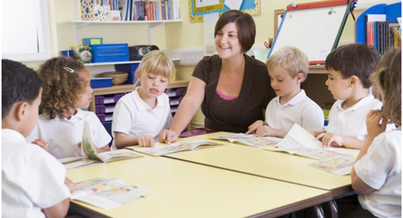Een juf met basisschoolkinderen om zich heen