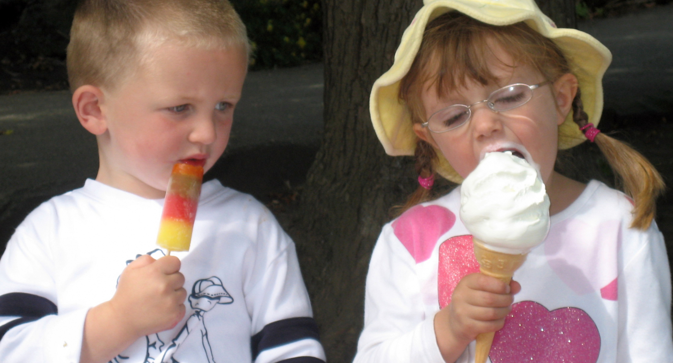 Jongen kijkt jaloers naar meisje met groter ijsje